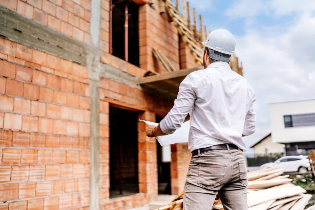 Engineer reading plans, inspecting the façade of a brick construction site